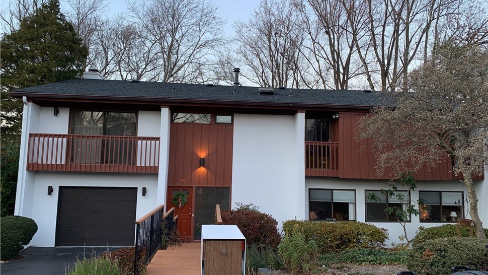 Two-story home in Reston, VA with a new Charcoal Timberline HDZ shingle roof, redwood accents, and a white exterior.