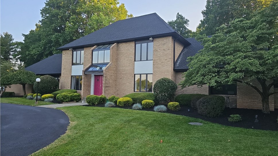 New roof installation with Charcoal Timberline HDZ shingles on a home in Bowie, MD with gorgeous blue sky and lush greenery in the background.