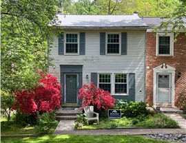 Two-story home in Reston, VA with a new Fox Hollow Timberline HDZ shingle roof, vibrant red azaleas, and a Shanco yard sign.