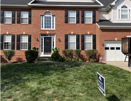 Front view of a brick home in Bowie, MD, with a newly installed Charcoal Timberline HDZ roof.