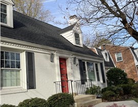White brick house in Bethesda, MD with a new Charcoal Timberline HDZ shingle roof and red front door.