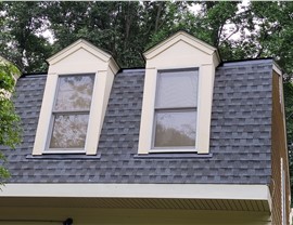 Close-up of a home in Silver Spring, MD, with a newly installed roof featuring Pewter Gray Timberline HDZ shingles, highlighting dormer windows and surrounded by greenery.