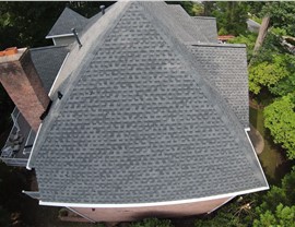 Aerial view of a brick home's new roof with Slate Timberline HDZ shingles, a brick chimney, and a deck surrounded by greenery in Midlothian, VA.
