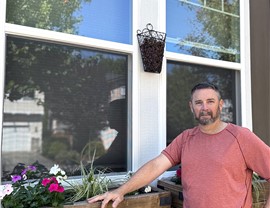 A Harley Exteriors customer standing in front of his new double hung windows in the front of his house.
