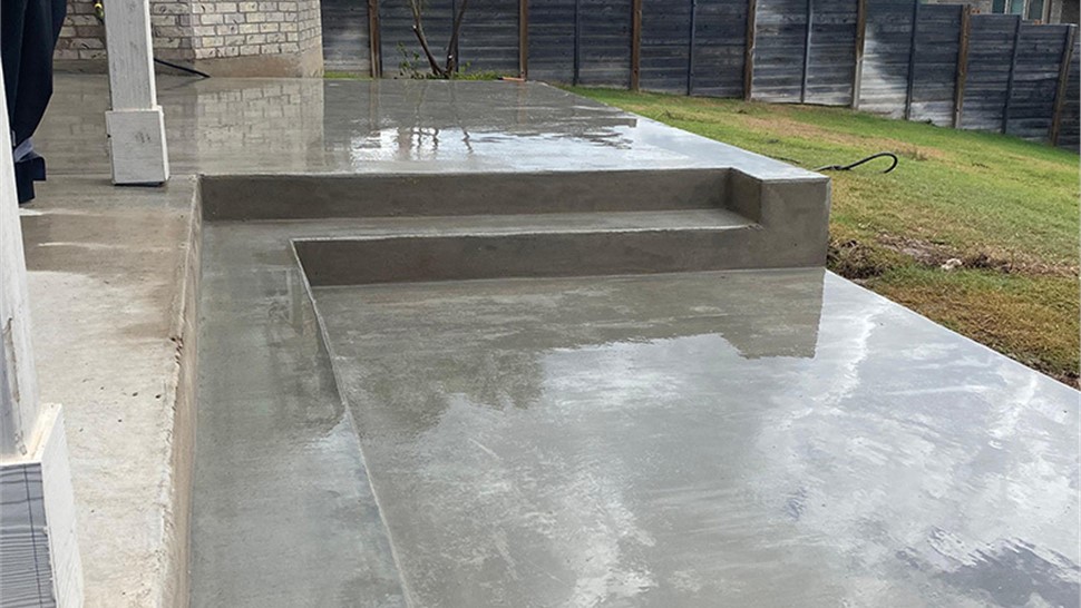 Freshly poured concrete patio with steps installed by JP Exteriors Outdoor Living for a backyard outdoor living area.