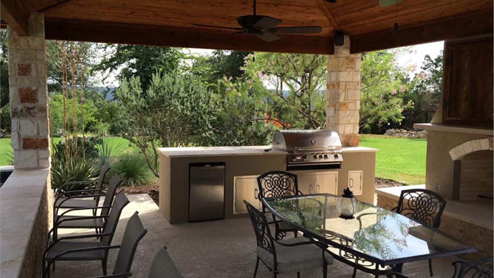 Custom outdoor kitchen with grill, refrigerator, and covered patio seating by JP Exteriors Outdoor Living.