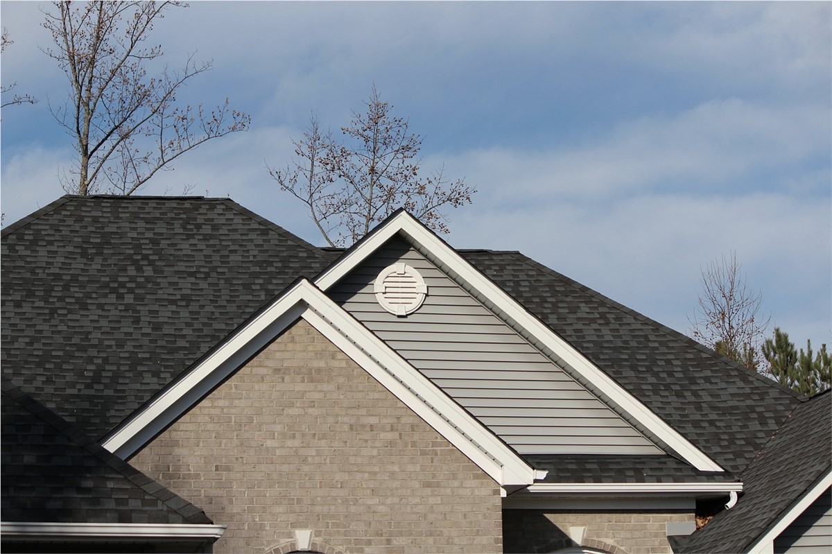 Roof line of a grey home with grey shingles.