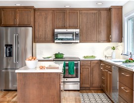 Warm wood kitchen with stainless steel appliances, quartz countertops, center island, and white tile backsplash.