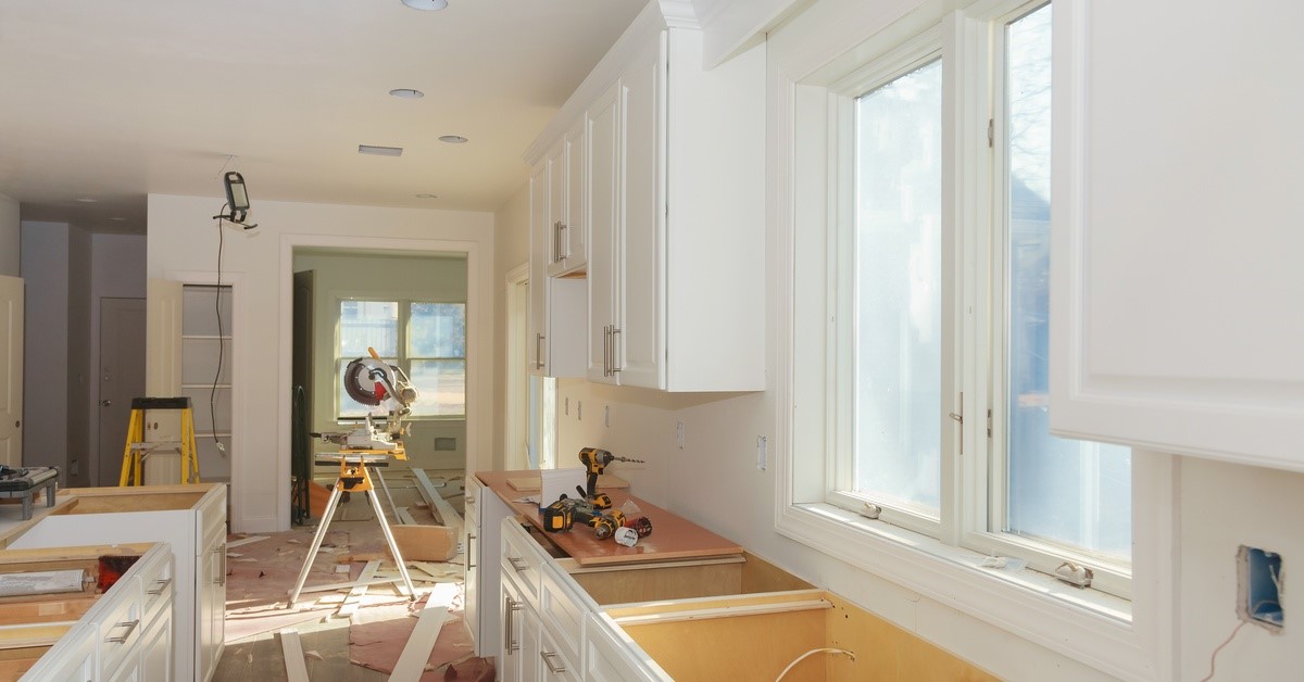 A residential kitchen is under construction. The counters are missing tops and outlets are missing covers.