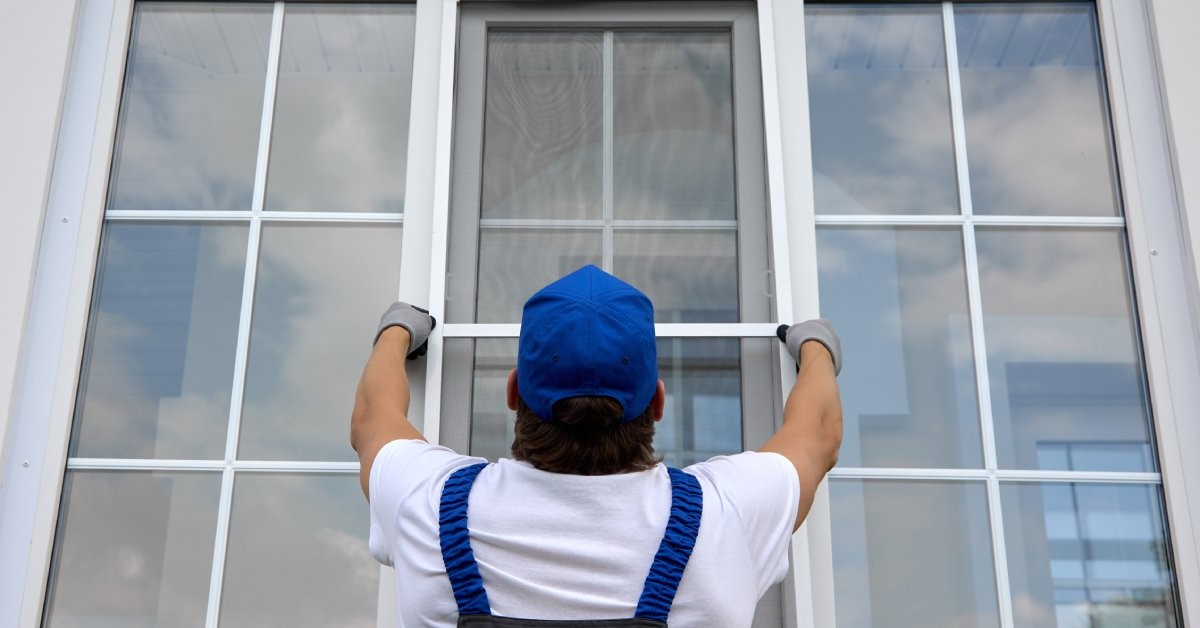  A professional contractor in uniform installing the finishing touches on his client’s newly installed windows.