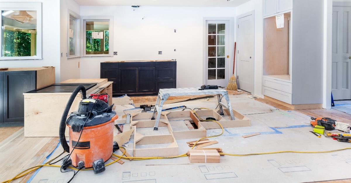 A residential kitchen is under construction. There are tools strewn about and the coiunters are missing their tops.
