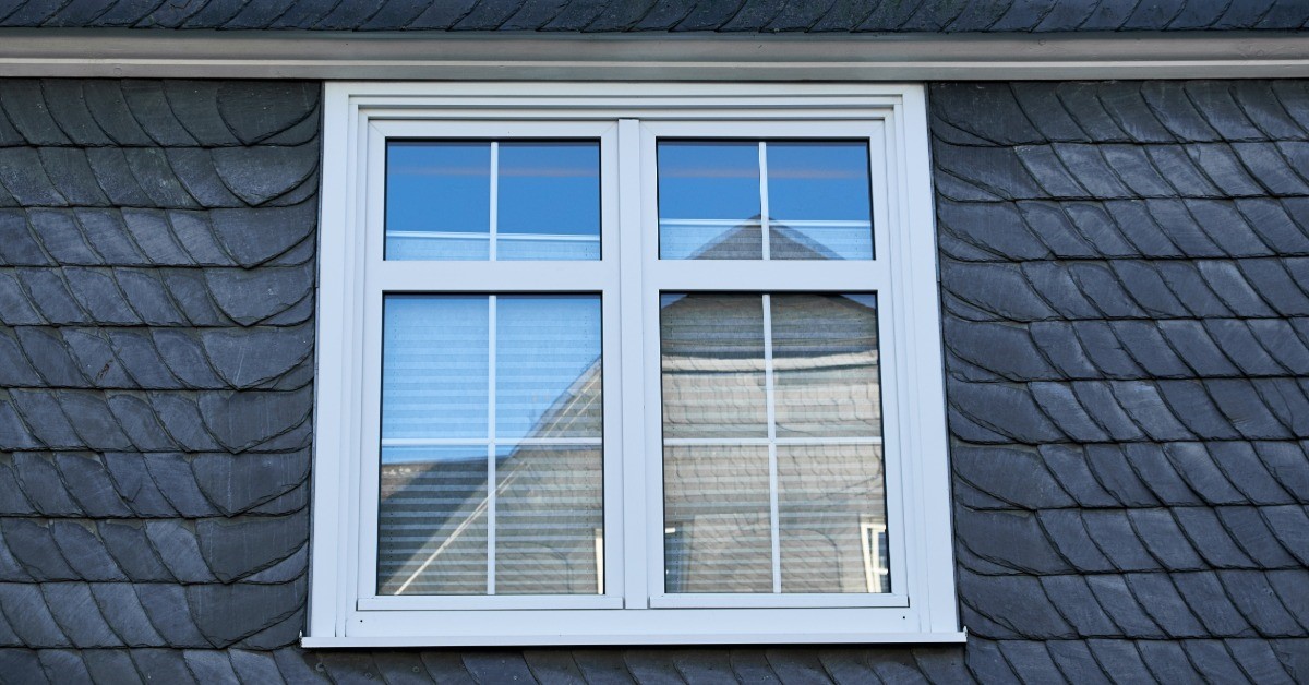 Three windows, all in a row, are installed on the side of a building. All three windows are open.