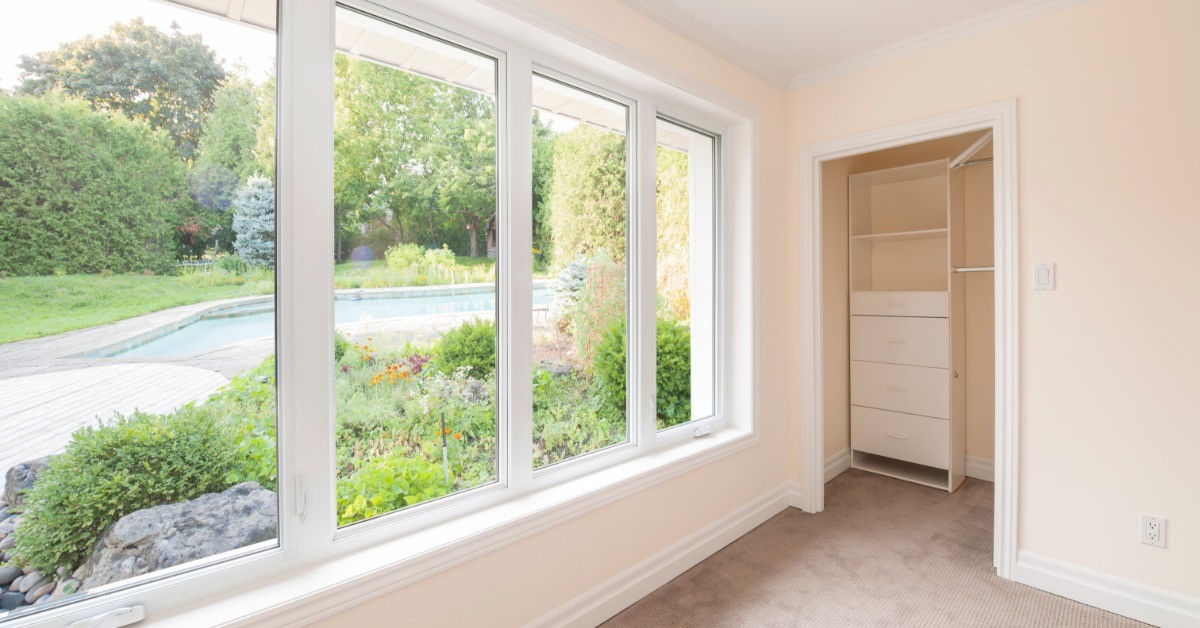 A picture window installed in a bedroom of a home. There is a closet with an open door but no clothes inside.