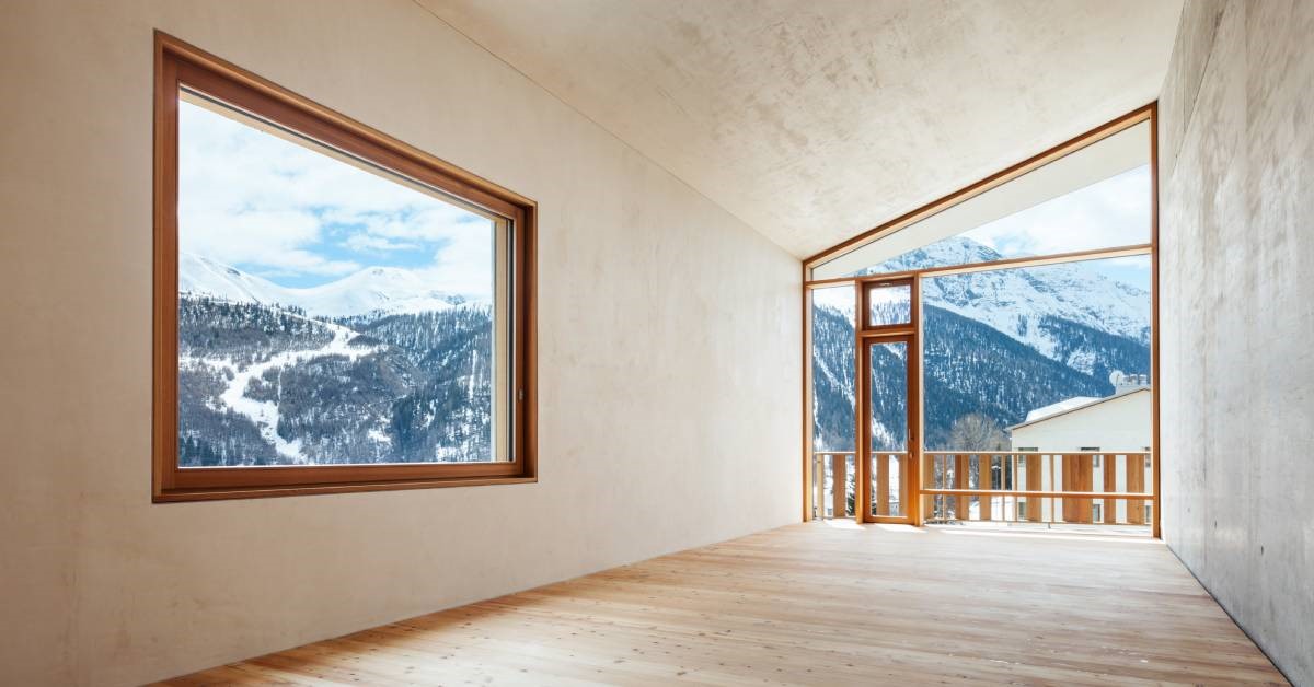 A spacious and modern mountain home interior, including large picture windows showcasing the scenic wilderness outside.