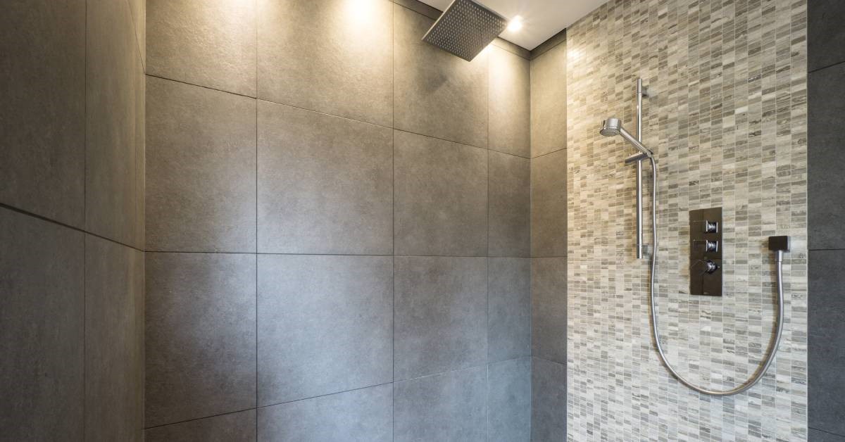 A residential shower boasting large marble stone tiles with an accent wall containing smaller granite stone tiles.