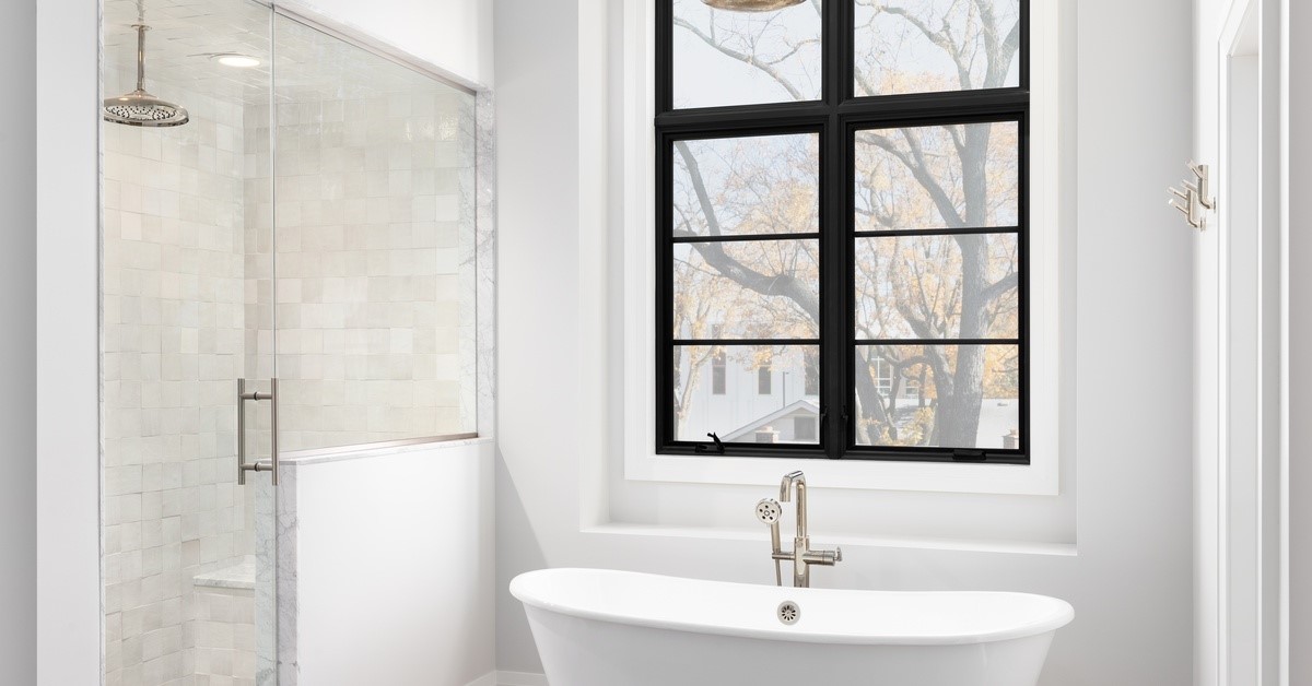 A bathtub is next to a shower. The shower has a glass door and a metal handle. The glass door is closed.