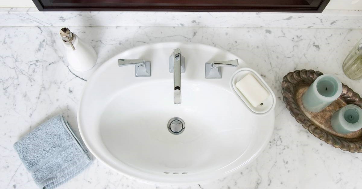 An overhead view of a bathroom sink featuring a countertop made from marble materials and a small sink basin.