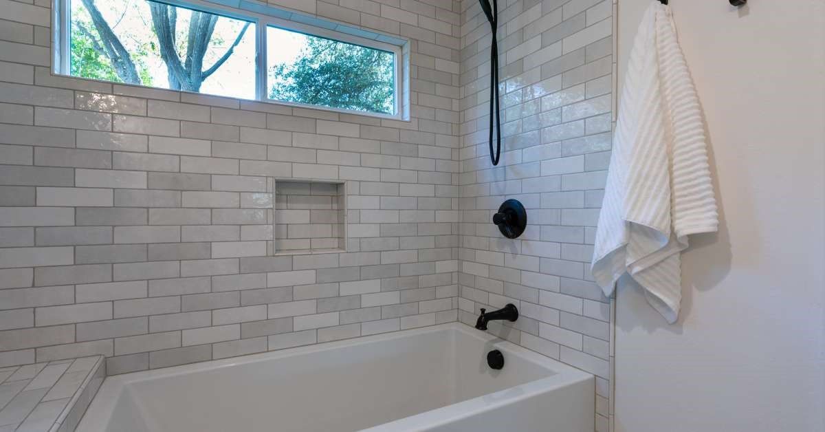 A modern residential restroom featuring a recently installed dual-purpose tub with a built-in showerhead.