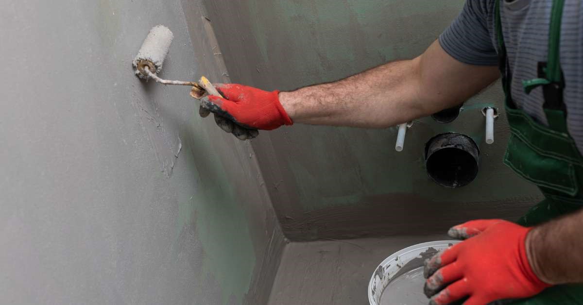 A professional contractor applying a liquid waterproof membrane to the walls of his client’s home restroom.