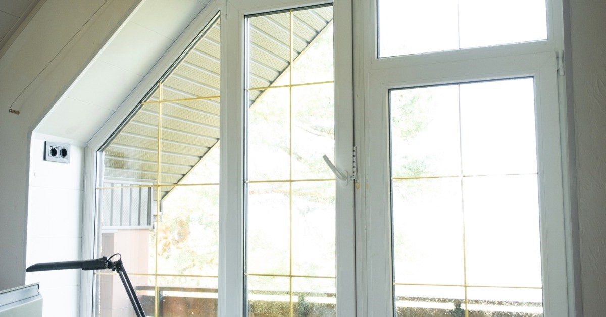Sunlight is shining through a window. Just beyond the window is a balcony with a wooden railing.