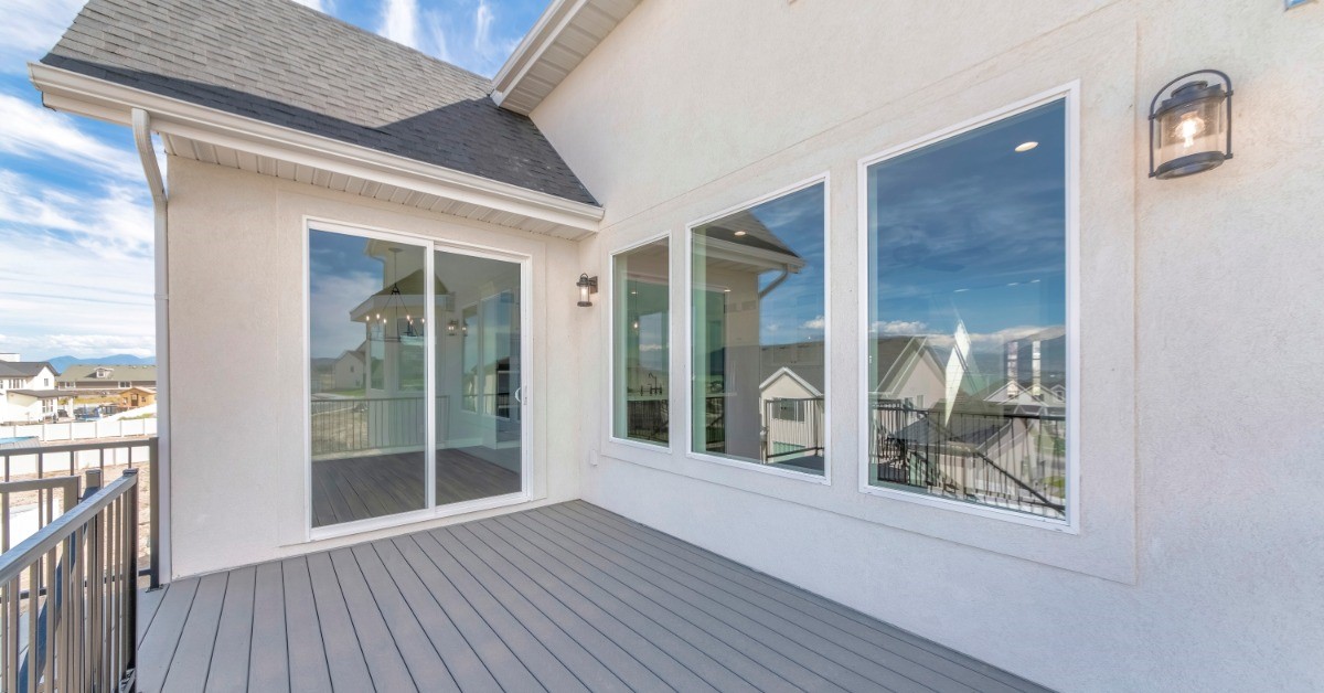 The exterior of a residential home that has a deck as well as a large picture window on the side of the house.