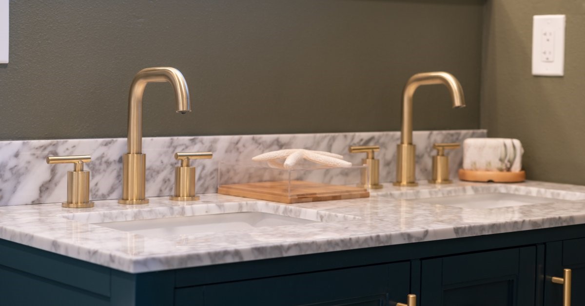 A modern double vanity in the corner of a bathroom, featuring gold hardware and a marble countertop.