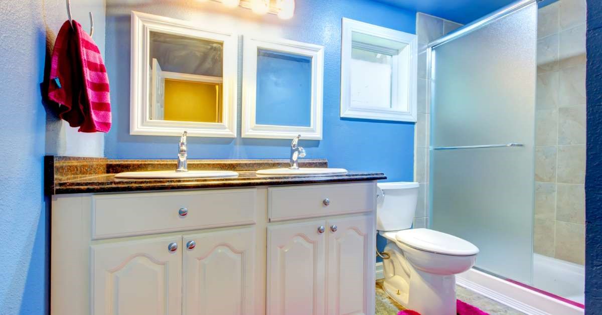 A recently renovated children’s bathroom, complete with bright blue painted walls and colorful floor rugs.