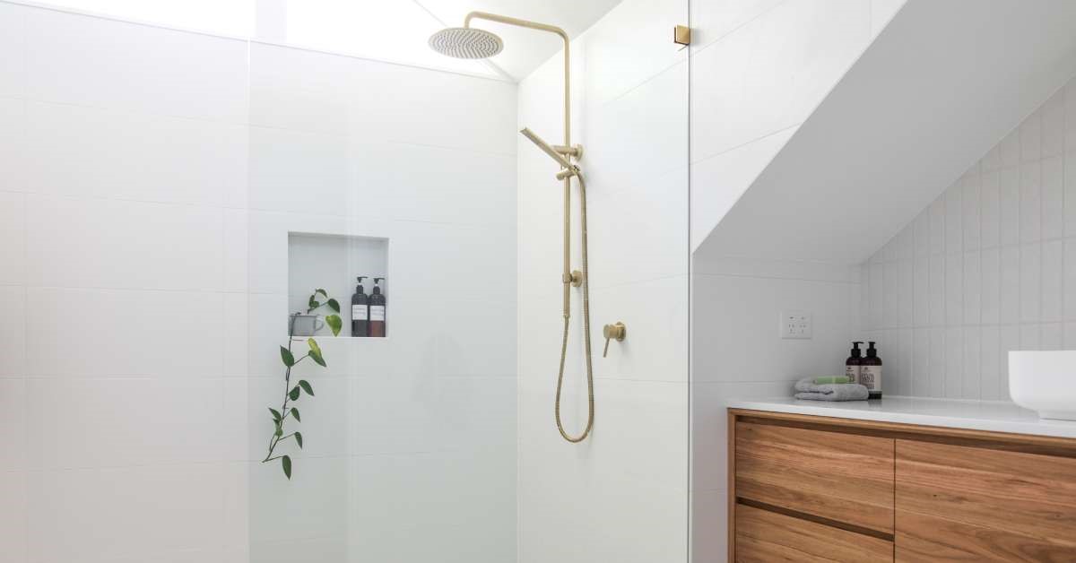 A modern residential home bathroom with a converted shower and open-concept glass door. The walls feature white tiling.