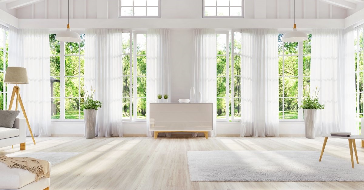 A large, mostly white interior of a residential sunroom, boasting large windows with plenty of natural light.