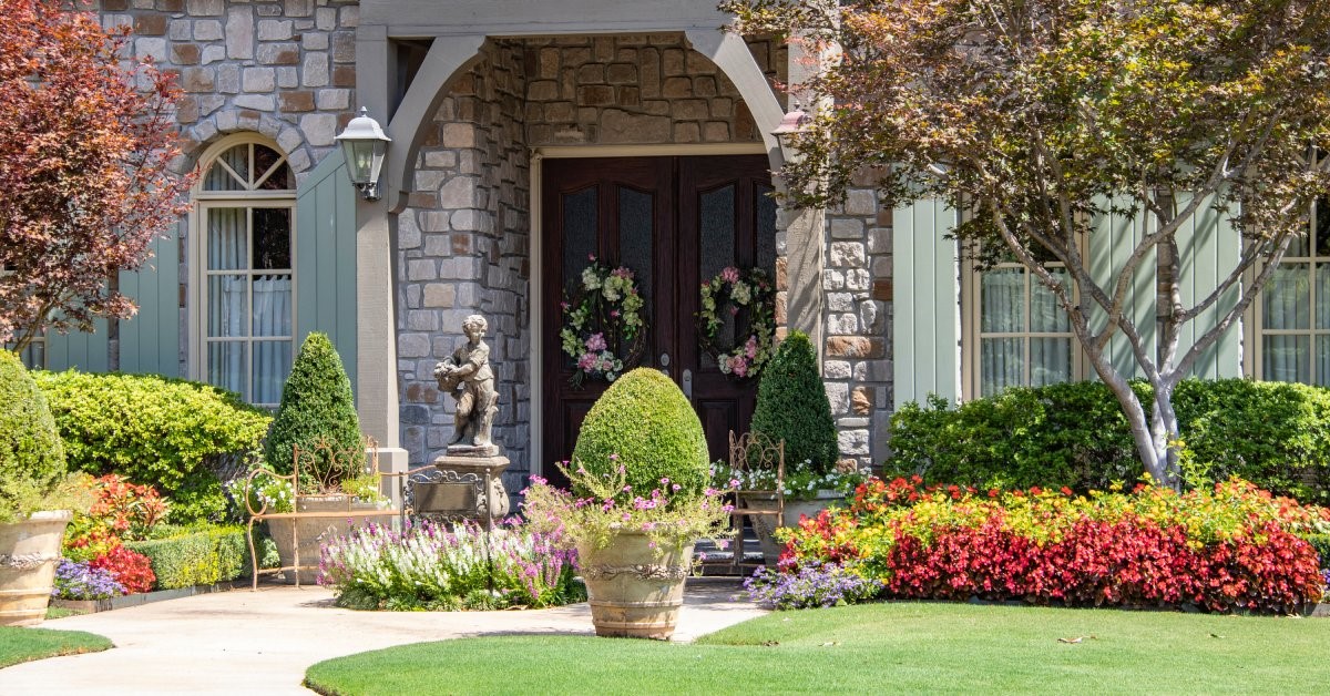  The front entrance of a residential home surrounded by well-maintained landscaping and lawn ornaments.