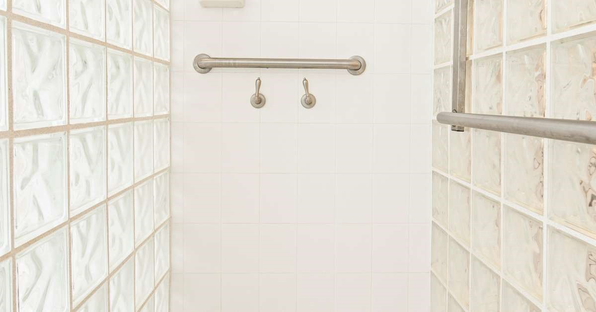 A wheelchair-accessible, highly safe home shower, complete with stainless steel grab bars on the walls.