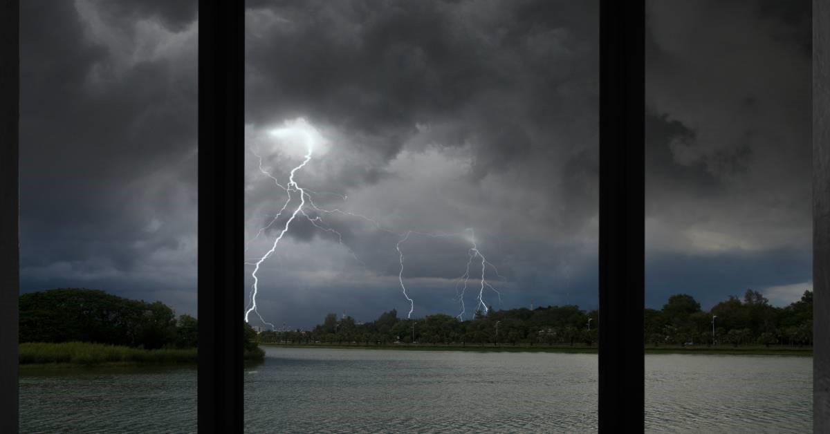 Lightning strikes and dark skies—a tropical storm—as seen from behind the panes of hurricane windows.