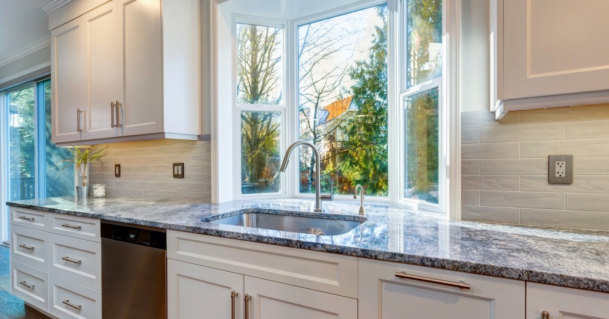 A recessed window with a white frame installed in a modern kitchen above the sink and counter.