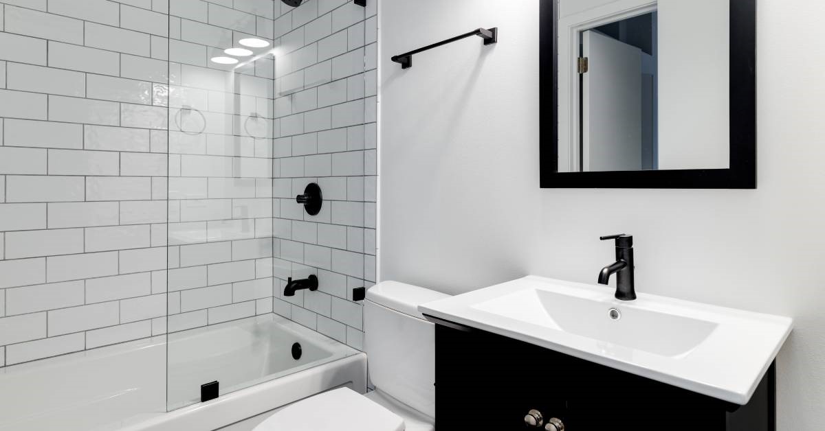 A small, modern residential bathroom featuring an open-concept shower with bright white shower tiles.