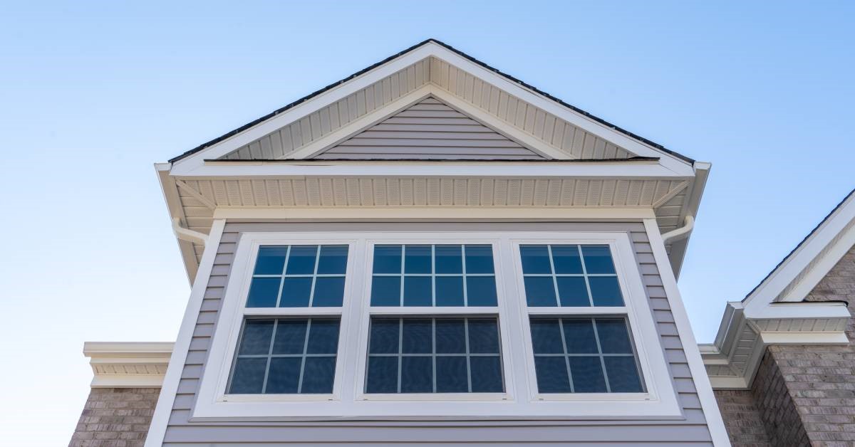 An exterior view of double-hung windows on the second floor of a house with brick and vinyl siding.