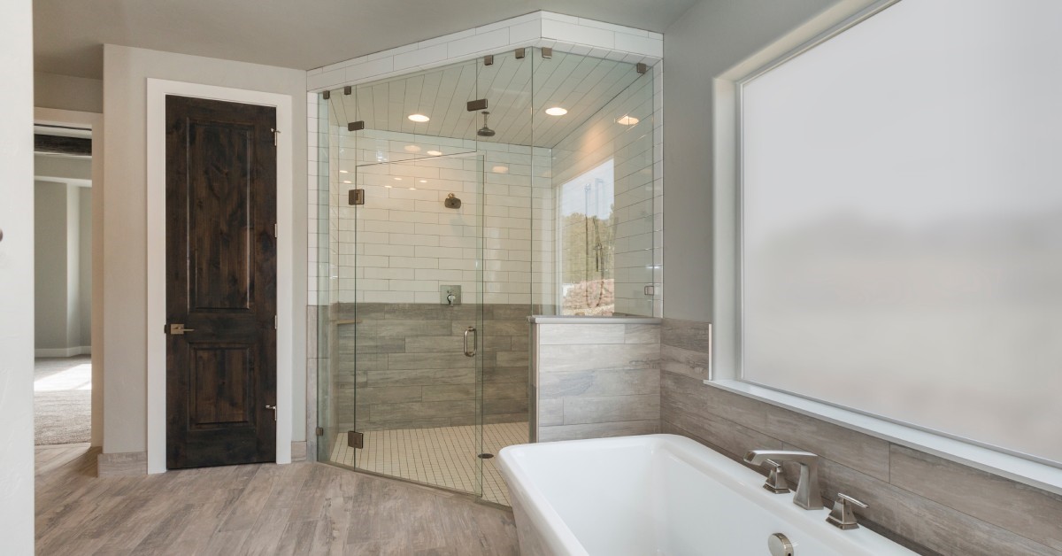 A modern, recently remodeled primary bathroom, including a redone glass shower and new soaking tub.