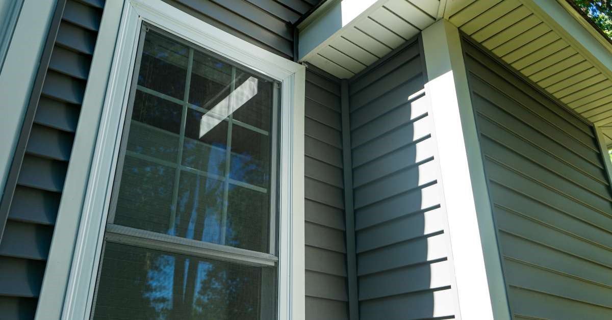 A brand new residential home with vinyl siding and window frames. The side window is treated with tinting materials.