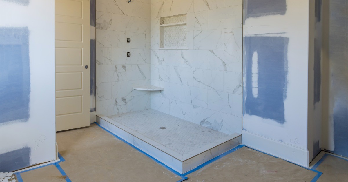 A bathroom is undergoing some construction and remodel. The shower is stripped down and has tape around it.