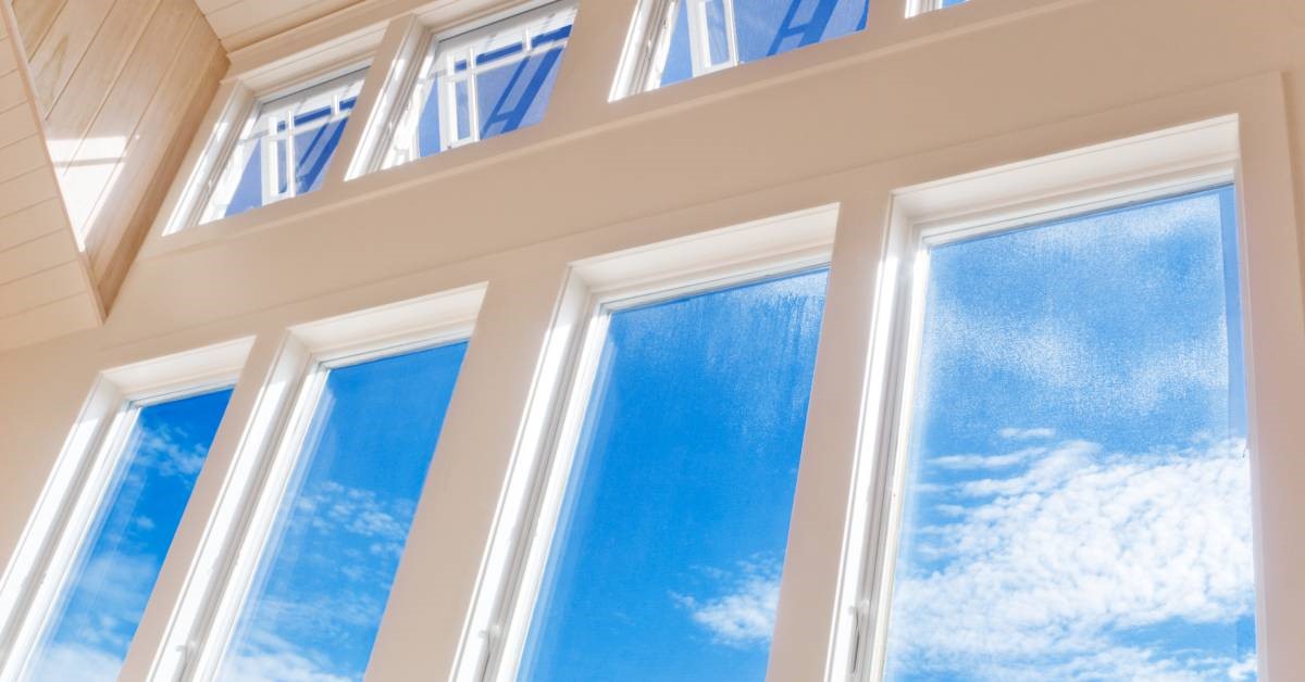 An interior view of a home, showcasing a wall of windows letting in plenty of sunlight and revealing a blue sky outside.