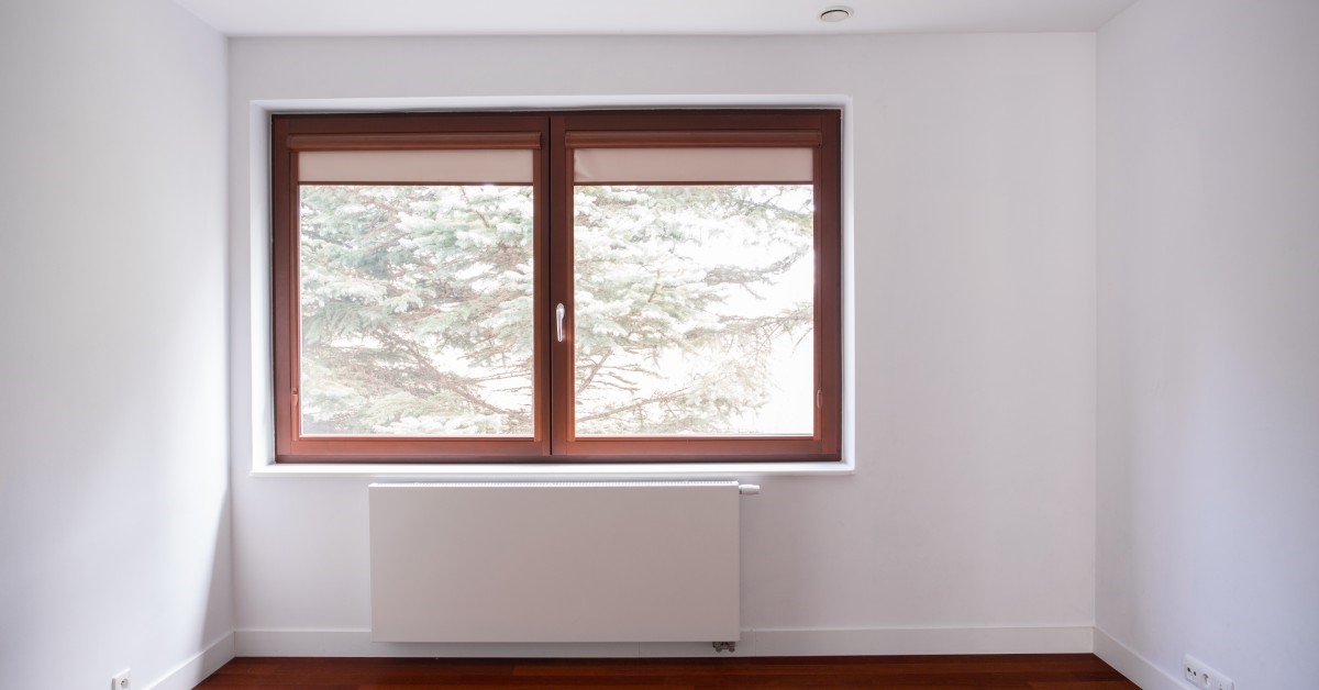 An unfinished room in a residential home, complete with brand-new casement windows, overlooking a pine tree.