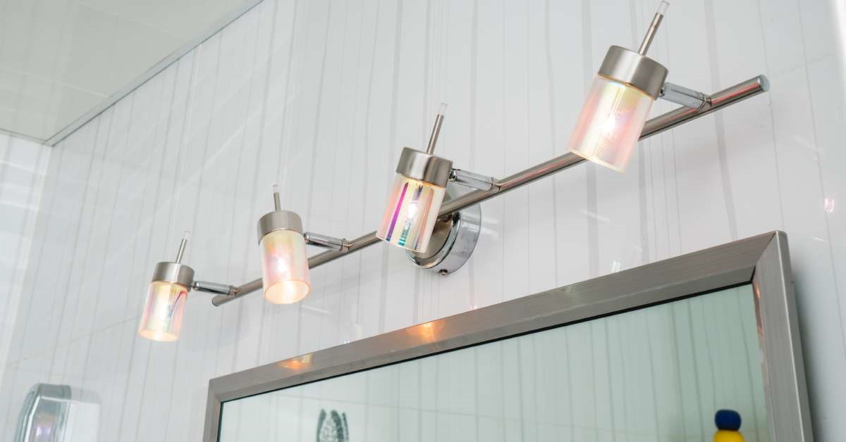 A close-up of a newly renovated bathroom mirror’s overhead lighting fixtures, providing suitable task lighting.