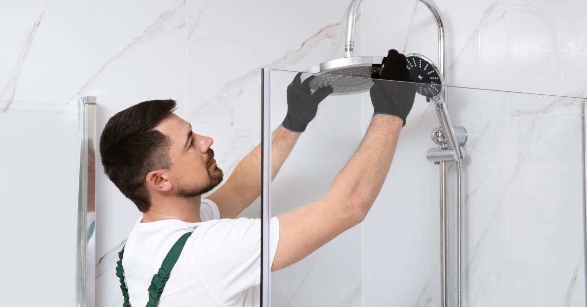 A contractor installing a dual-functional showerhead—the finishing touch for his tub-to-shower conversion.