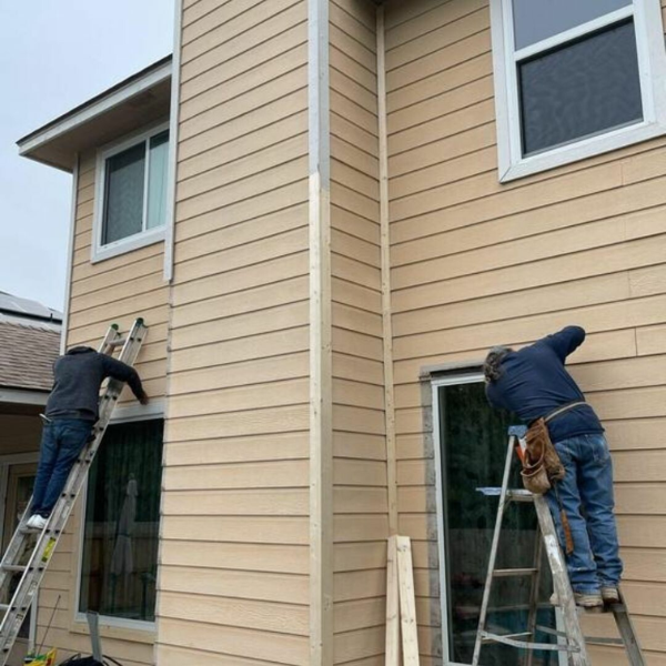 An image showing a team of professionals installing concrete fiber siding on a house.