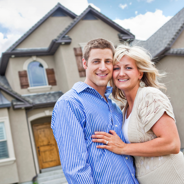 An image showing a happy homeowner in front of a well-maintained house.