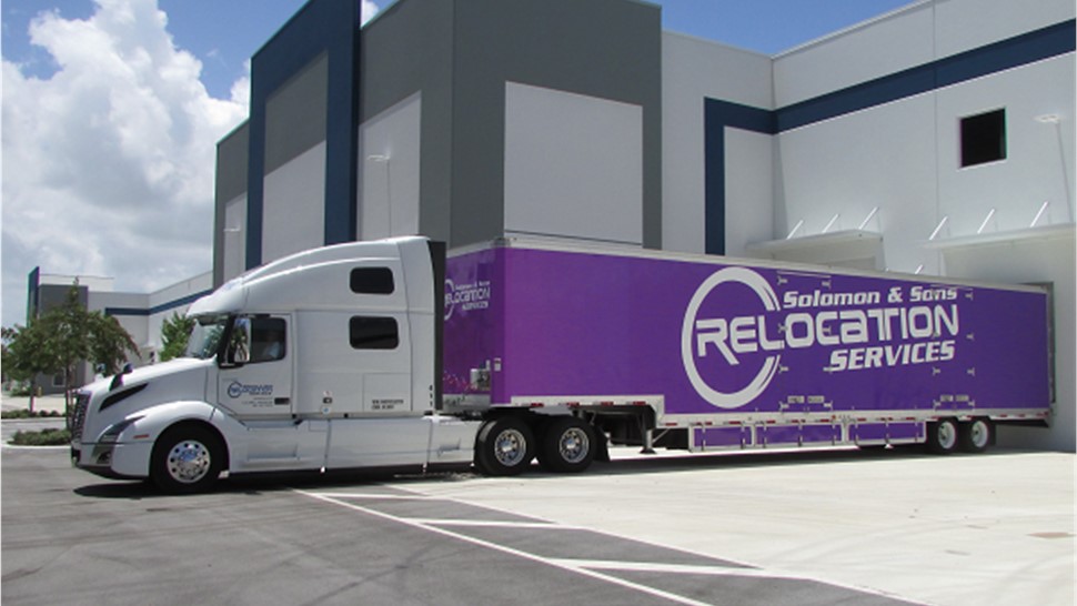 Purple Florida moving truck docked at warehouse.
