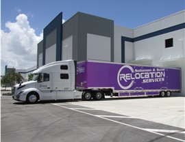 Purple Florida moving truck docked at warehouse.