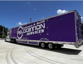 Purple Fort Lauderdale moving truck pulling out of warehouse.