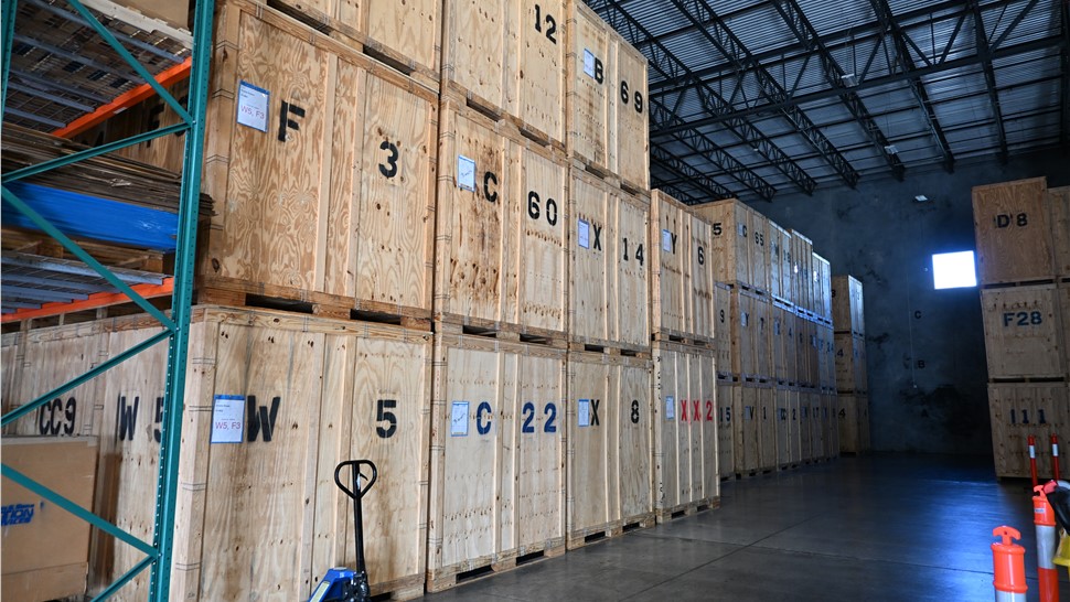 Warehouse aisle with stacked wooden storage vaults and a pallet jack used for commercial storage.