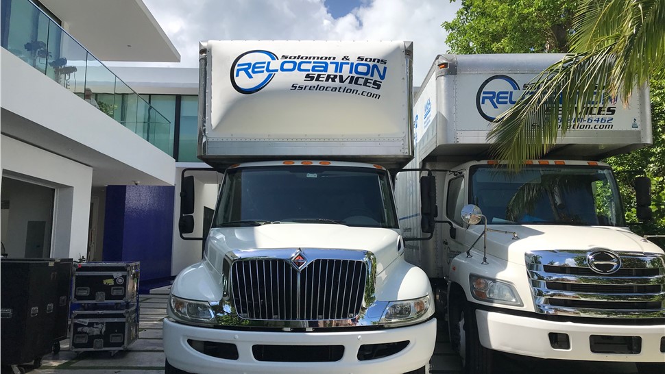 Two Solomon & Sons moving trucks parked at a modern Florida home during a residential move.