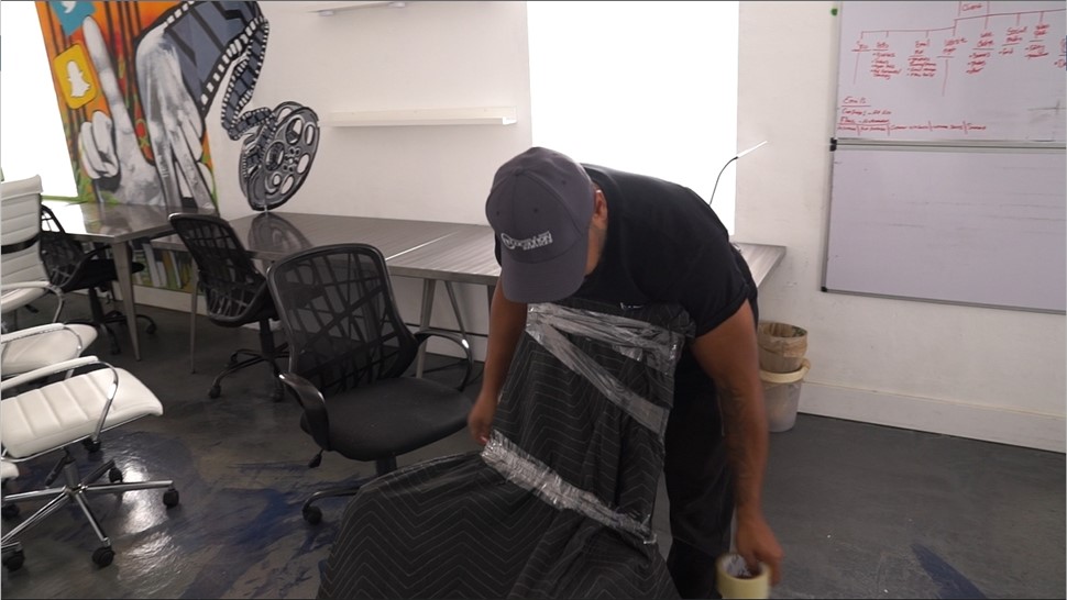 Mover wrapping an office chair with a moving blanket and stretch wrap to protect it during an office move.